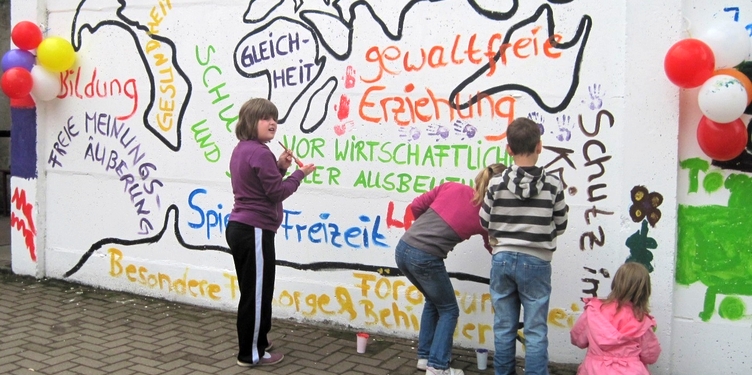 Kinder schreiben Wörter an eine Wand