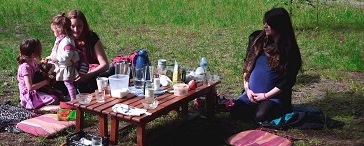 Zwei Frauen mit Kindern bei einem Picknick auf einer Wiese