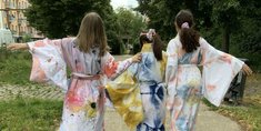 Drei Mädchen, mit selbstgestalteten Kleidern, gehen einen Weg entlang